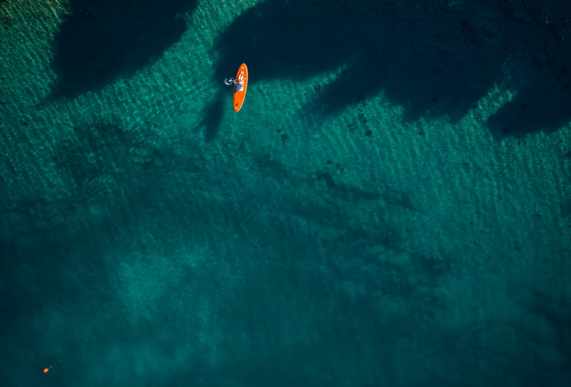 Un paddle orange vu du ciel, au-dessus des fonds marins