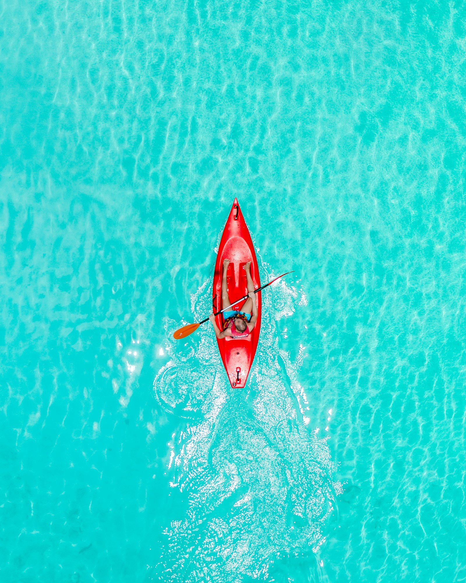 Un kayak rouge vu du ciel, sur une eau très claire